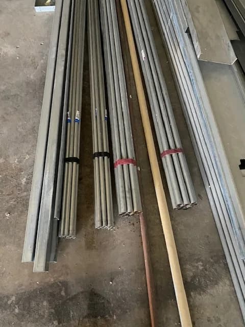 Bundles of EMT conduit and copper staged on the slab