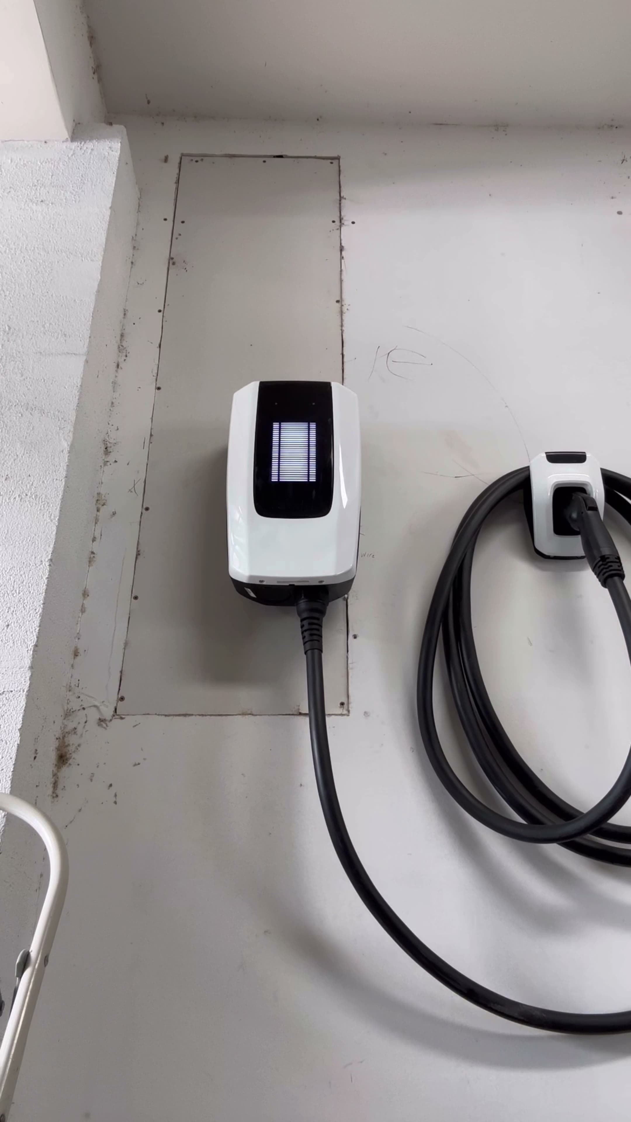 Wall-mounted white Level 2 EV charger with connector holstered — finished install